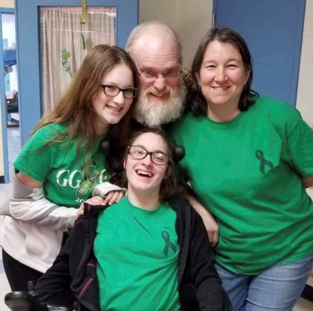 Four members of the Fogel family next to each other smiling, wearing green t-shirts for cerebral palsy awareness