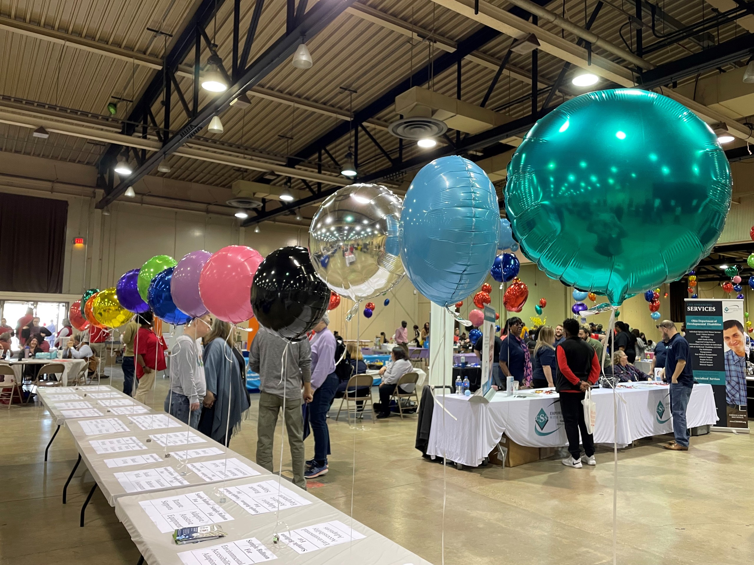 colorful ballons attached to tables in crowded event hall