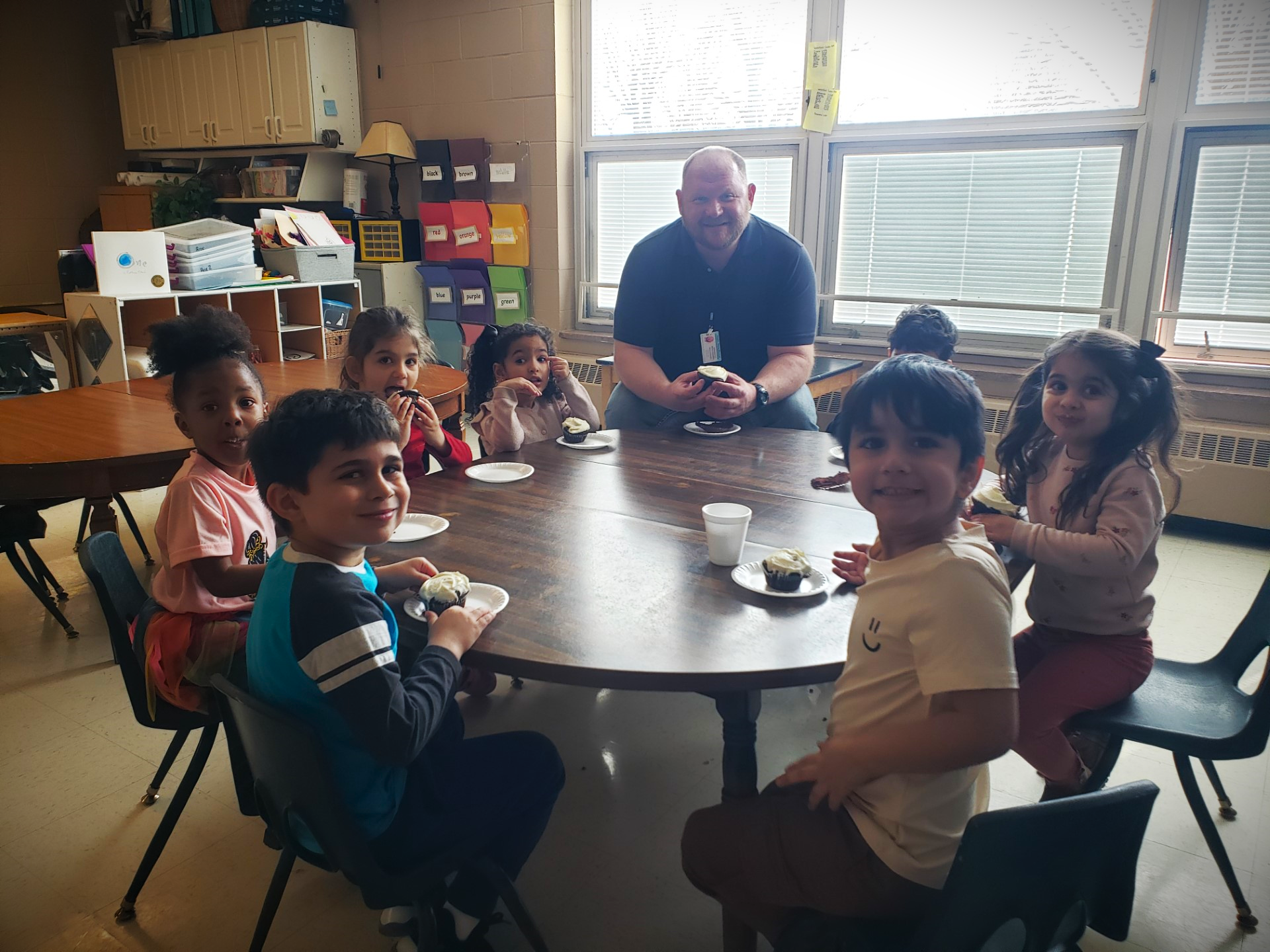 man sitting at table with group of preschoolers
