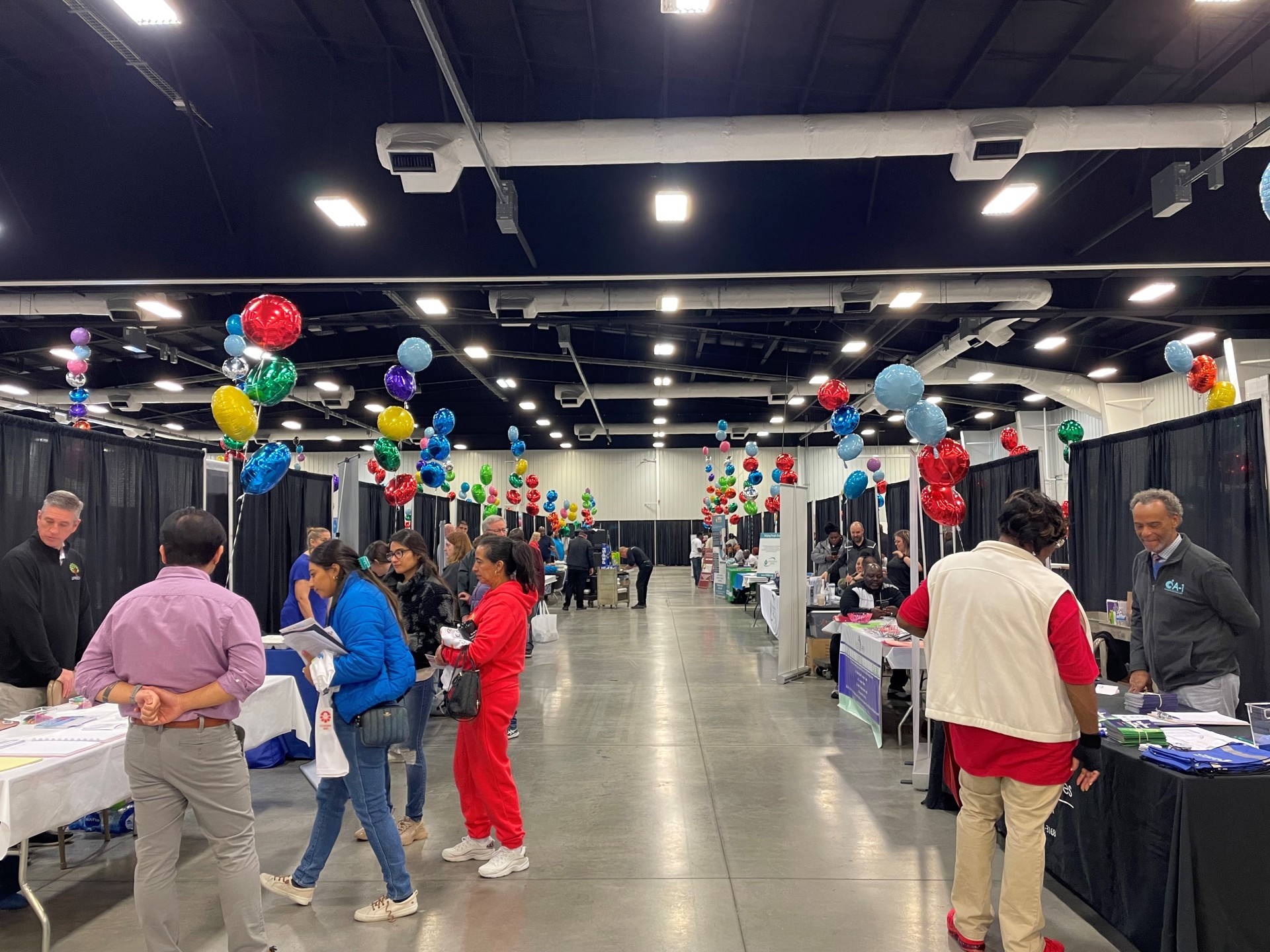 Many people inside large hall lined with resource tables.