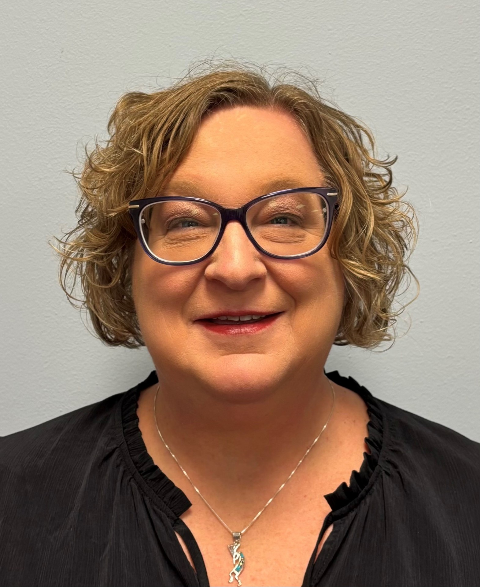 Smiling woman with short, curly hair and glasses