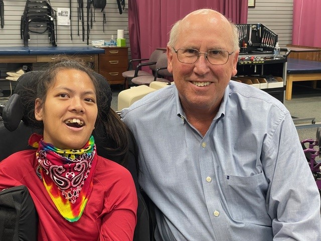 Smiling older man next to young woman in wheelchair